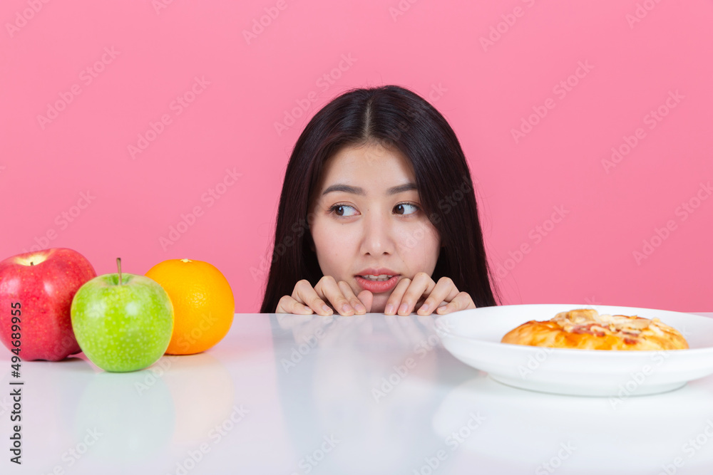 happy young asian woman choose to eat fresh orange apple fruits with copy space pink background, health care eat vegetables and useful foods lifestyles concept. happy young asian woman choose to eat fresh orange apple fruits with copy space pink background, health care eat vegetables and useful foods lifestyles concept.