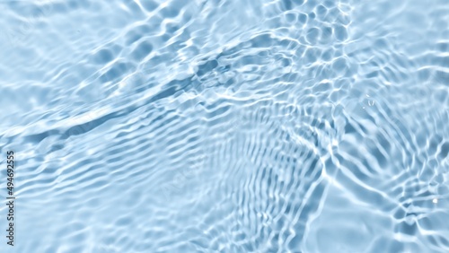 Multiple waves of water cross each other creating ripples spontaneously on pale blue background | Beauty background shot for skin care cosmetics advertisement