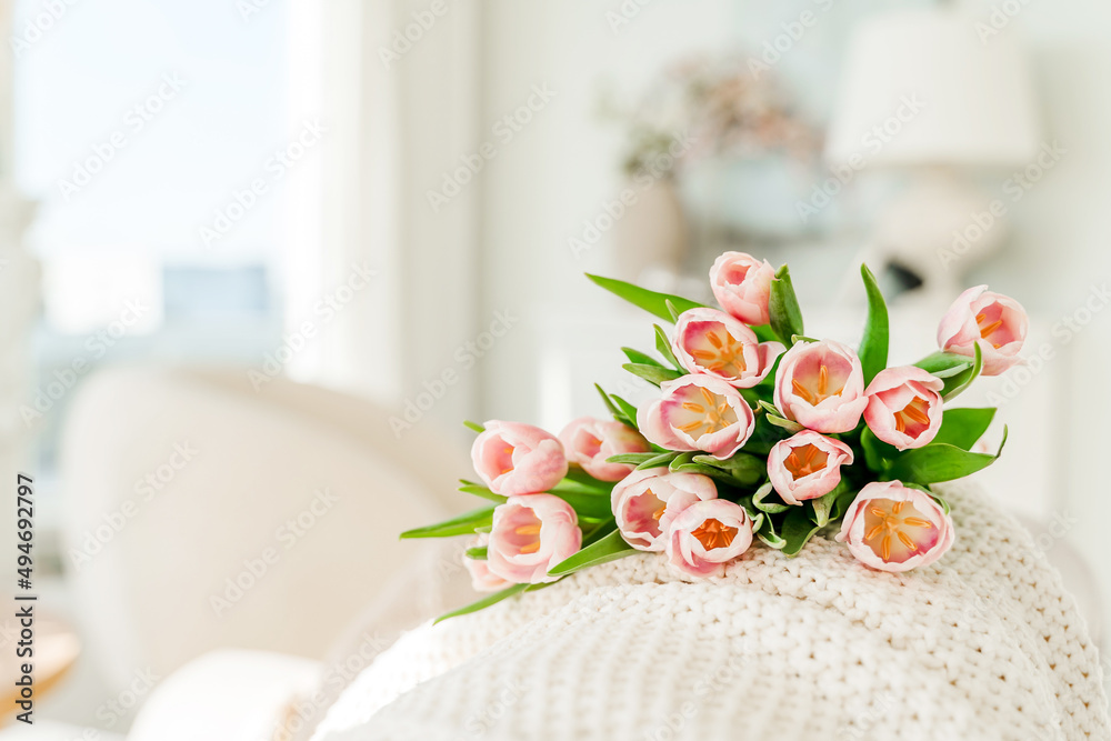 Spring concept with pink tulips lying on a blanket in a bright modern interior. A beautiful banner for spring and summer. Spring concept with pink tulips lying on a blanket in a bright modern interior. A beautiful banner for spring and summer.