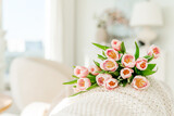 Spring concept with pink tulips lying on a blanket in a bright modern interior. A beautiful banner for spring and summer.