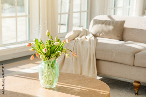 A bouquet of tulips in a beautiful vase at home in a bright modern interior on a wooden table. Spring concept