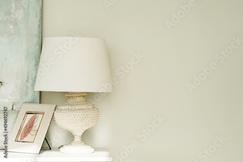 Detail of a bright modern room with a white lamp on the chest of drawers and an empty wall for your text