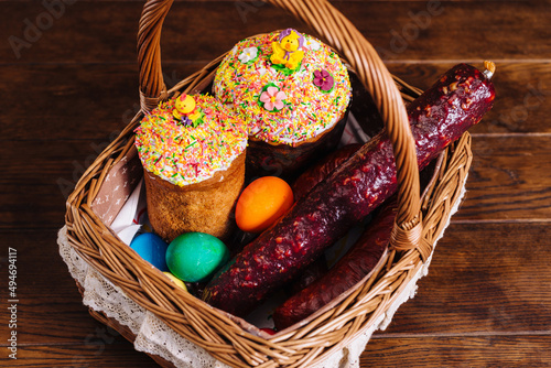 Easter basket with ukrainian easter cake, sausage and Easter eggs on wooden table. Orthodox Easter