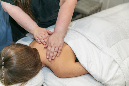 Close up of a female message therapist giving a woman a shoulder massage at a local spa