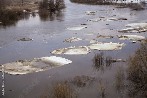 Bild auf Leinwand Lined up in a row, small white ice floes float along the river