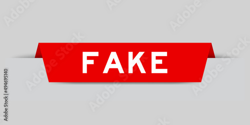 Red color inserted label with word fake on gray background