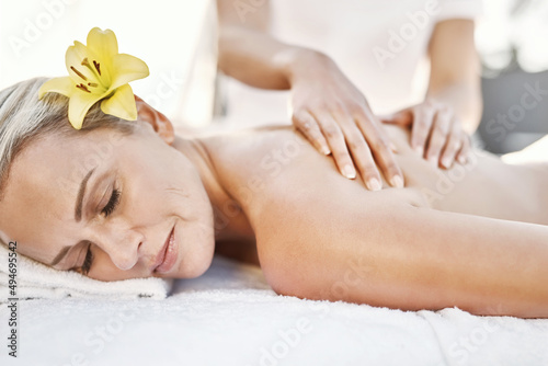 Vacations are the best. Shot of a relaxed middle aged woman lying on her stomach while receiving a massage at a spa outside during the day.