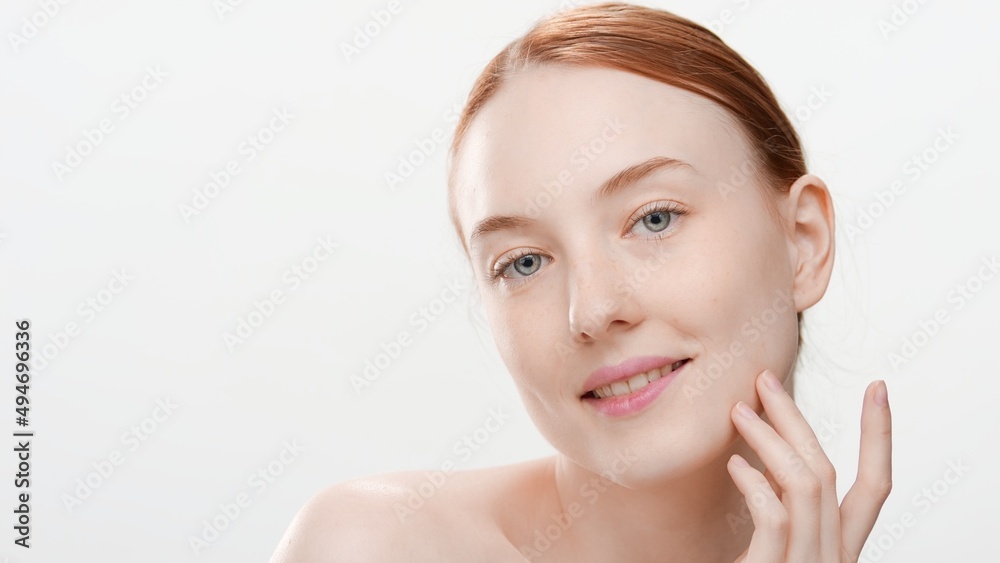 Attractive slim young red-haired Caucasian woman with bare shoulders touches her jawline smiling wide for the camera on white background | Skin renewal concept Attractive slim young red-haired Caucasian woman with bare shoulders touches her jawline smiling wide for the camera on white background | Skin renewal concept