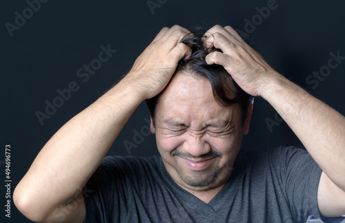 Middle age man has itching in his hair on black background,