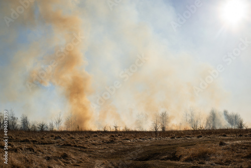 Photo of clouds of smoke burning grass and trees in early spring. Dangerous wildfire because of dry weather