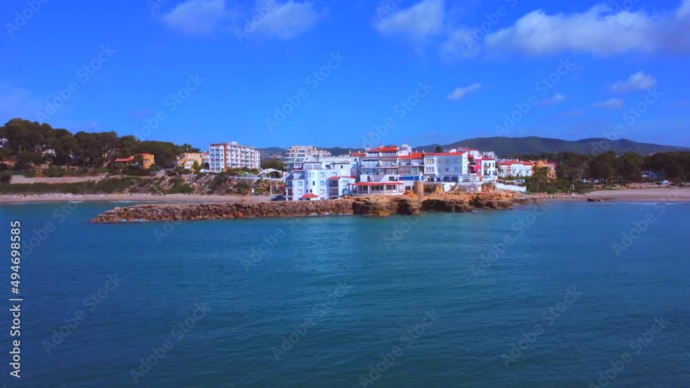 Traveling from left to right along the coast. Houses entrance to the port of the CATALAN in Spanish COAST. Houses on breakwater breakwater. Sunny day. Aerial view along the coast. Drone view Traveling from left to right along the coast. Houses entrance to the port of the CATALAN in Spanish COAST. Houses on breakwater breakwater. Sunny day. Aerial view along the coast. Drone view