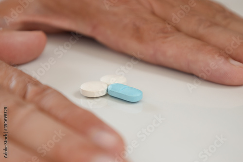 Colored pills forming small male genitalia in the hands of a man on a neutral background. Male impotence treatment concept.