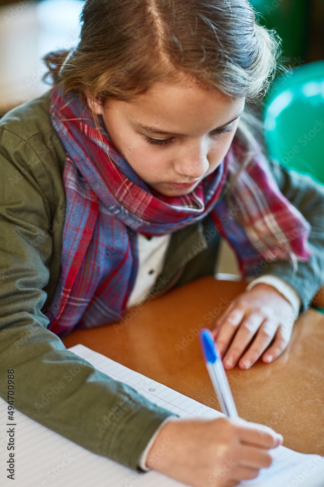 Shes all about finishing her schoolwork. Cropped shot of an elementary school girl doing her school work in the classroom. Shes all about finishing her schoolwork. Cropped shot of an elementary school girl doing her school work in the classroom.