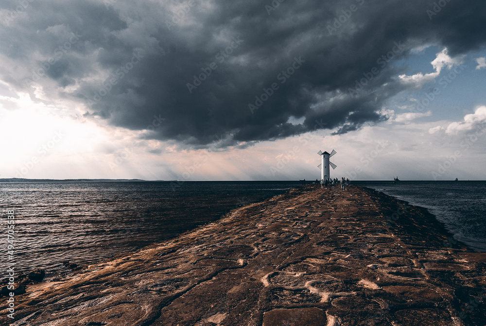 Świnoujście, Poland - June 2021: Stone breakwater, Lighthouse at sunset