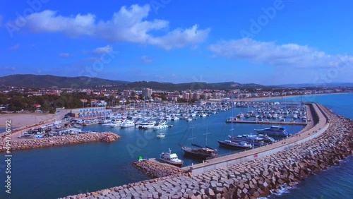 Traveling from left to right along the coast. Boat departure from the port of Creixell in CATALuña in Spain. Breakwater jetty. Sunny day. Aerial view bordering the port. Drone view. photo