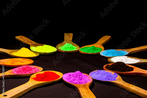 colourful powder paint in wooden spoon on black fabric in black background with copy space.powder paint is a natural color that humans use.