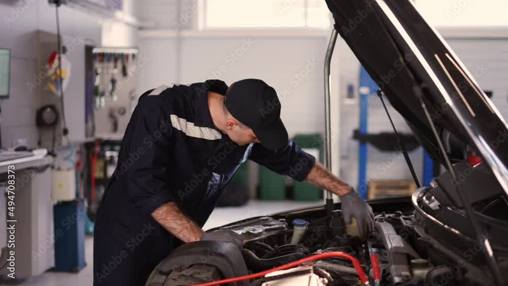 Mechanic in a auto repair shop checking engine manually Mechanic in a auto repair shop checking engine manually