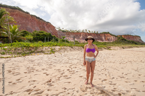 Lady standing at the beach known as Taipe with the colorful cliffs in the background near Arraial d’ Ajuda, Biaha, Brazil  photo