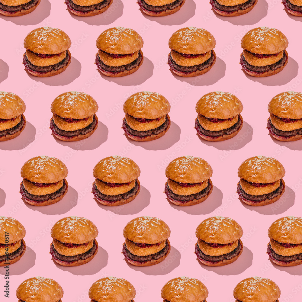 Creative burger pattern with beef patty, camembert and cherry on a pink background. minimal style