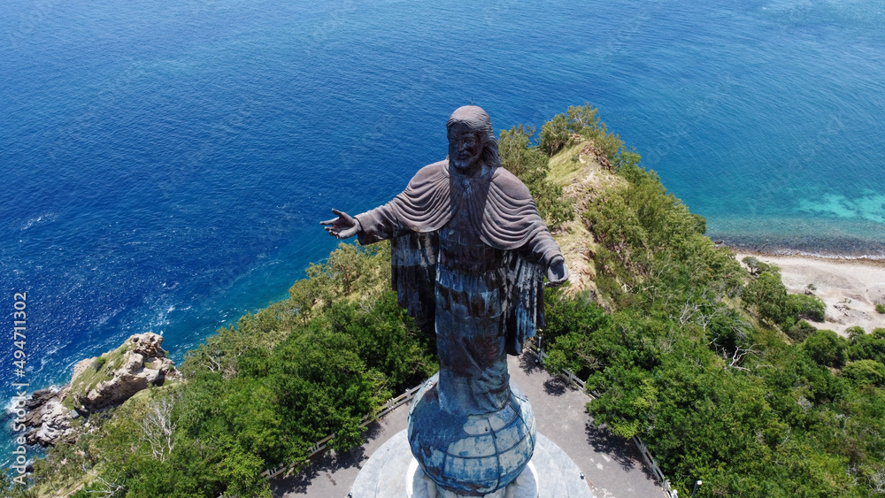 The Cristo Rei of Dili Jesus Christ statue with stunning blue ocean backdrop in capital Dili, Timor Leste, aerial drone view of tourism landmark