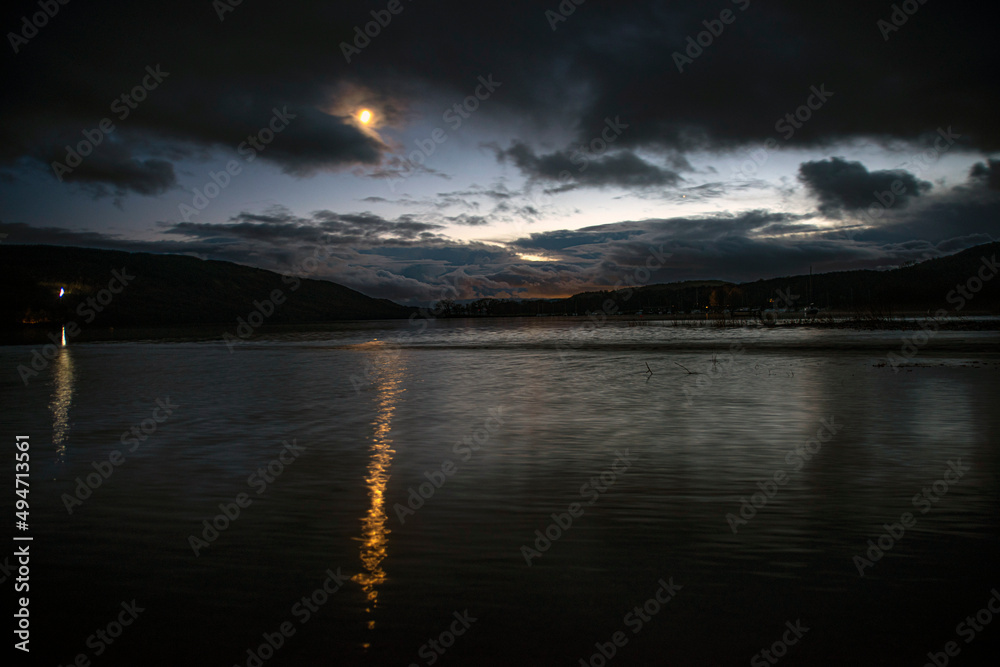 Coniston Lake at Night With moon and Reflactions on Water with moon coming out from behind clouds