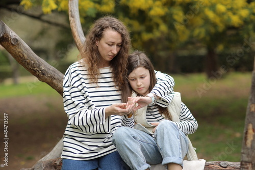 young mother and daughter are hugging in the blooming spring park. Mom and child spending time together, having fun at the mimosa orchard. Mother's, baby's day day