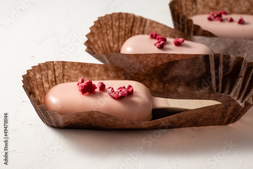 Cake in the form of popsicle on sticks in paper packaging close-up. Cheesecake on a stick. Selective focus.