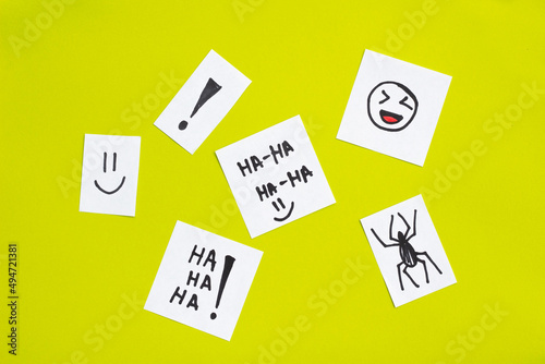joke concept sketched on pieces of paper. Ha ha text and drawn spider, laughing emoji on green background. April Fool's Day. April 1