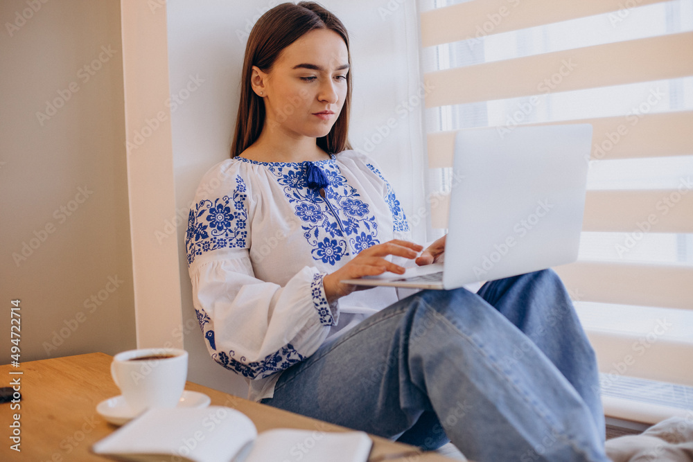 Fototapeta premium Young ukrainian woman wearing vyshyvanka working from home