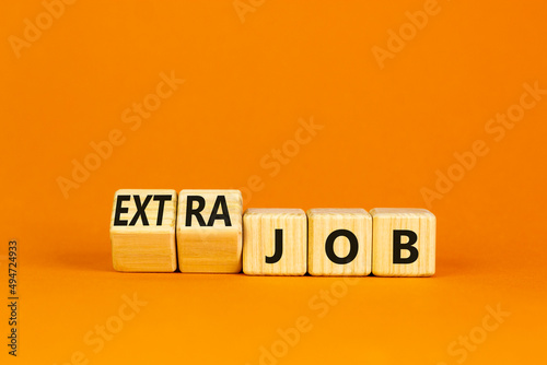 Extra job symbol. Turned wooden cubes and changed concept words Job to Extra job. Beautiful orange table orange background, copy space. Business extra job concept.