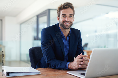 Confident about business. Shot of a young businessman sitting at a desk in front of a laptop.