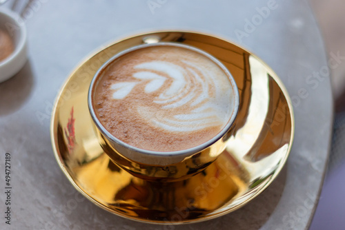 Latte with cream in golden glass. Latte art. Coffe on table.