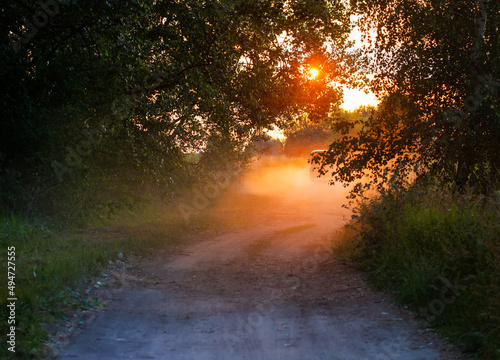 Summer sunset and a lonely car on a dusty road. Warm colors high contrast photo. photo