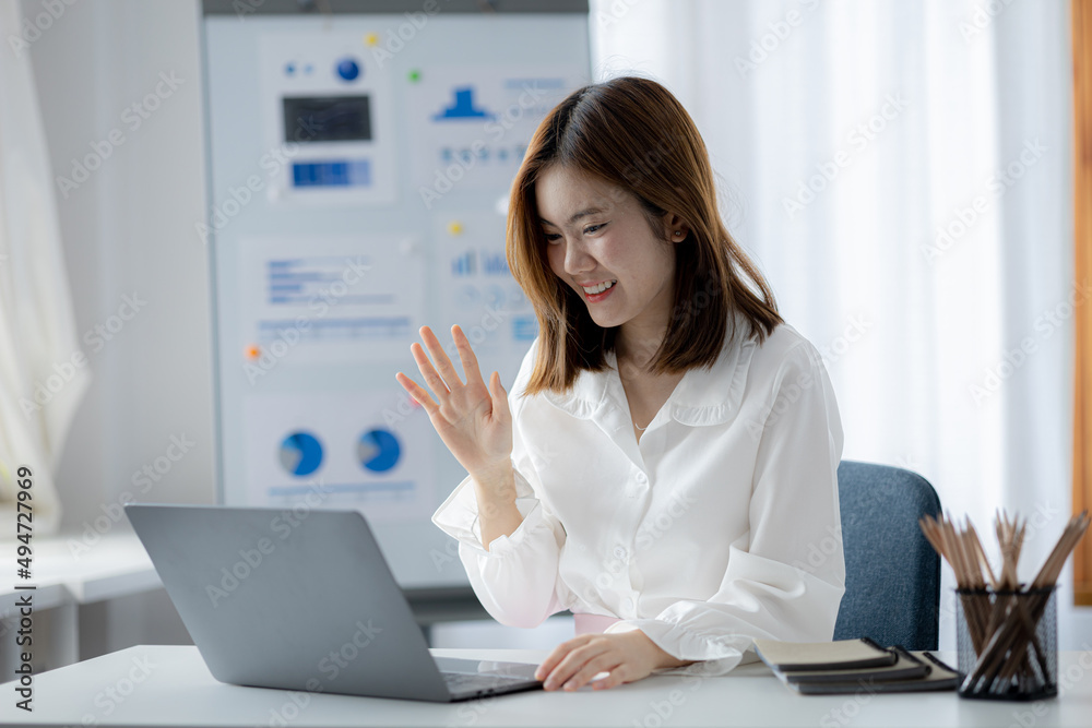 Beautiful Asian businesswoman sitting in her private office, she is talking to her partner via video call on her laptop, she is a female executive of a startup company. Concept of financial management Beautiful Asian businesswoman sitting in her private office, she is talking to her partner via video call on her laptop, she is a female executive of a startup company. Concept of financial management