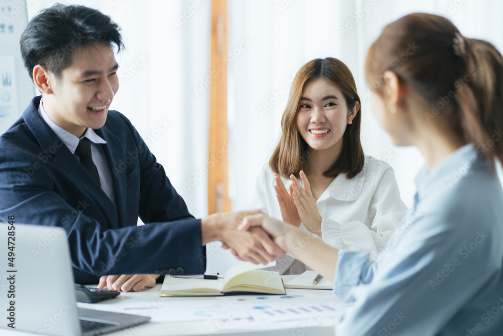 Group of beautiful designers in casual clothes is discussing affairs and smiling while working in studio. Two of them are shaking their hands Group of beautiful designers in casual clothes is discussing affairs and smiling while working in studio. Two of them are shaking their hands