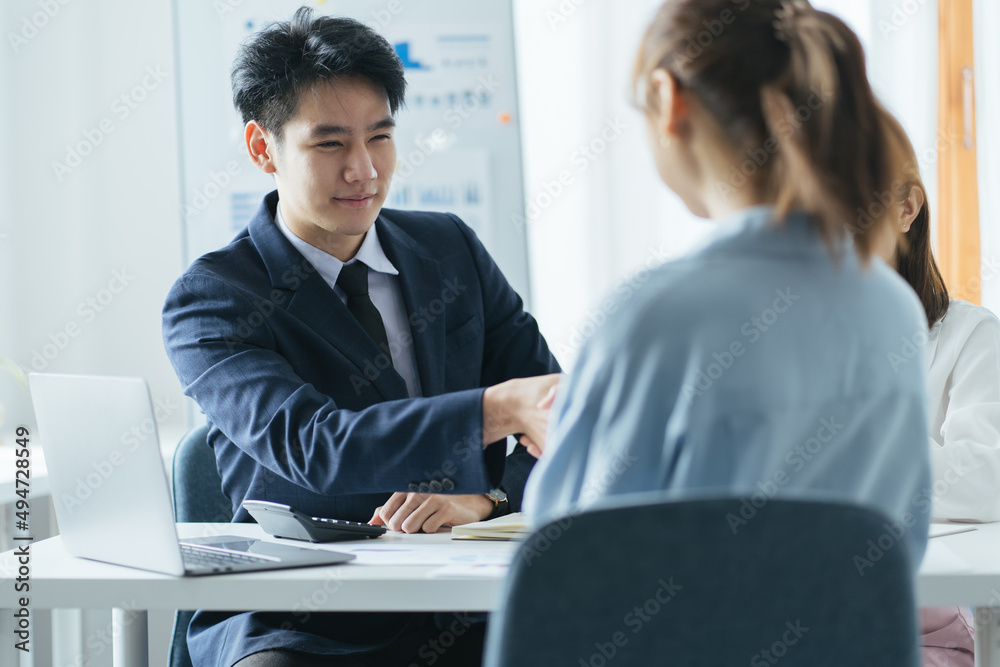 Group of beautiful designers in casual clothes is discussing affairs and smiling while working in studio. Two of them are shaking their hands Group of beautiful designers in casual clothes is discussing affairs and smiling while working in studio. Two of them are shaking their hands