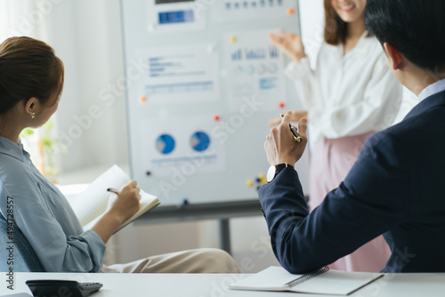 Three colleagues are concentrated on data at the flipchart  disscussing the solutions of their company s problems and sharing opinions and ideas  in light modern workplace wearing smart clothes