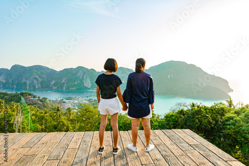Behind woman and girl standing at the view-point of Phi Phi Don Island and looking to the island.