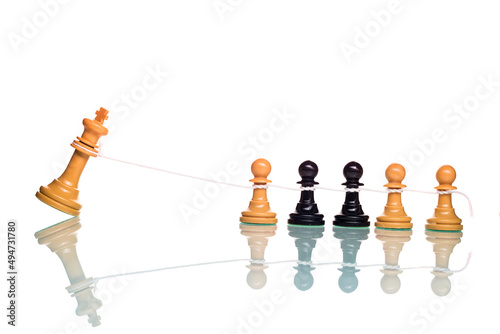 Chess pawns overthrowing the white king with a rope. photo