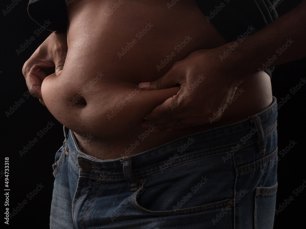 Naklejka premium Fat man squeeze the stomach on black background. Health care concept.