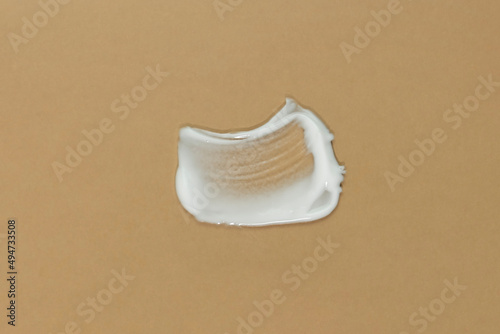 White cream texture on a beige background. Smear of skincare cosmetics product. Wellness and beauty concept