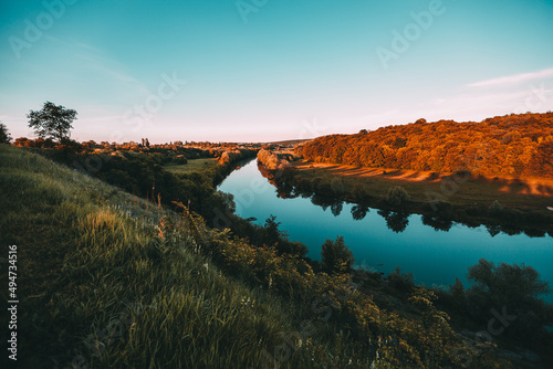 Picturesque landscape near the city with the sunset green grass and blue river