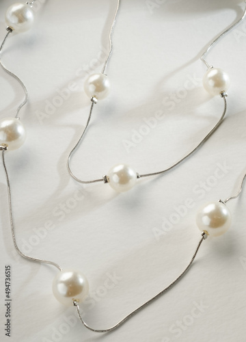Fashion jewelry - double silver chain with white beads on a white background.