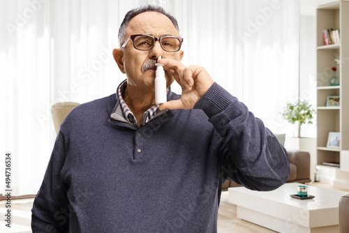 Mature man using a nasal spray at home photo