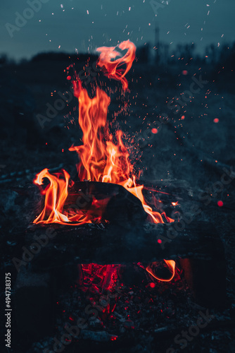 Big red flame with sparks and bokeh on the dark background in night