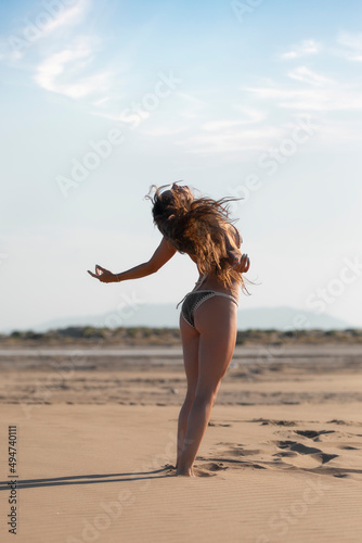 Chica joven en la playa realizando posiciones de baile y yoga