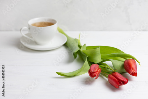 A cup of tea, delicate tulip flowers on a concrete background. Birthday greeting card, wedding.