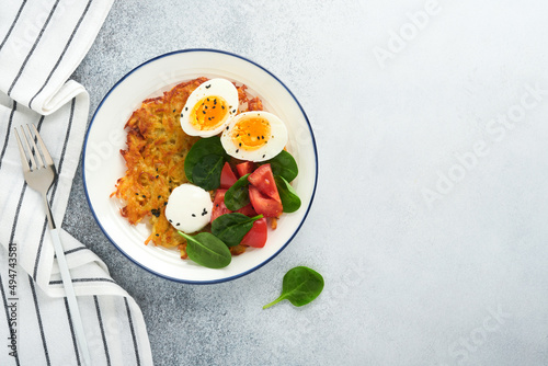 Breakfast. Potatoes latkes with sour cream, spinach salad, tomatoes and boiled eggs on light background. Delicious food for breakfast. Top view.
