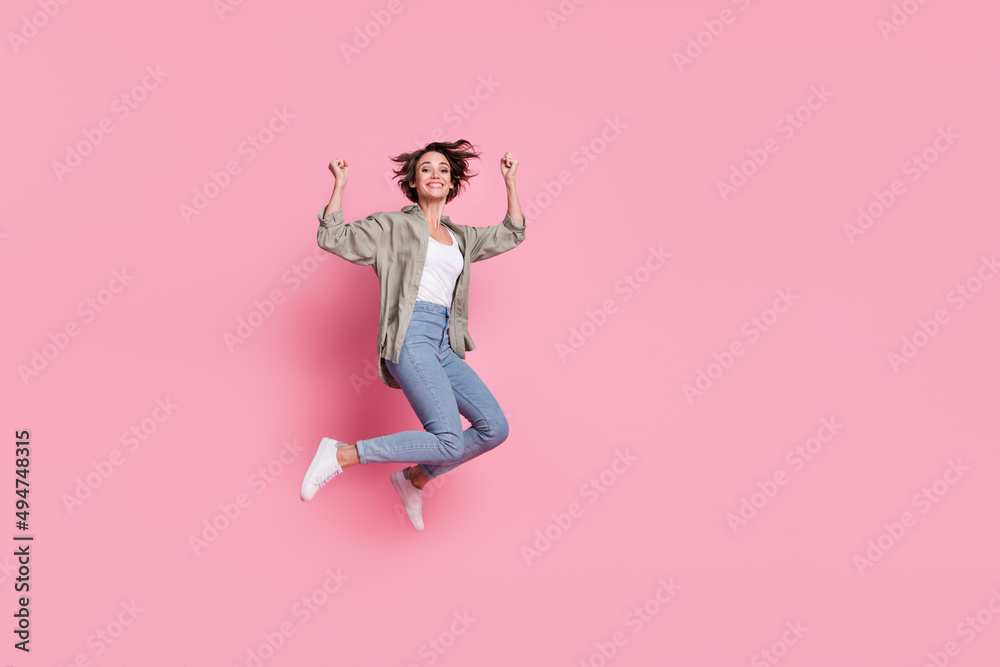 Full length photo of young woman jump rejoice success lucky fists hands triumph isolated over pink color background
