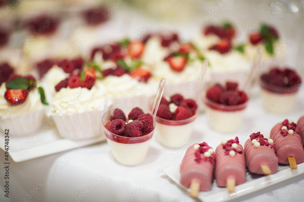 Delicious dessert of cake with fresh strawberries, raspberries and mint leaf. Banquet table full of fruits and berries and an assortment of sweets. Candy bar.